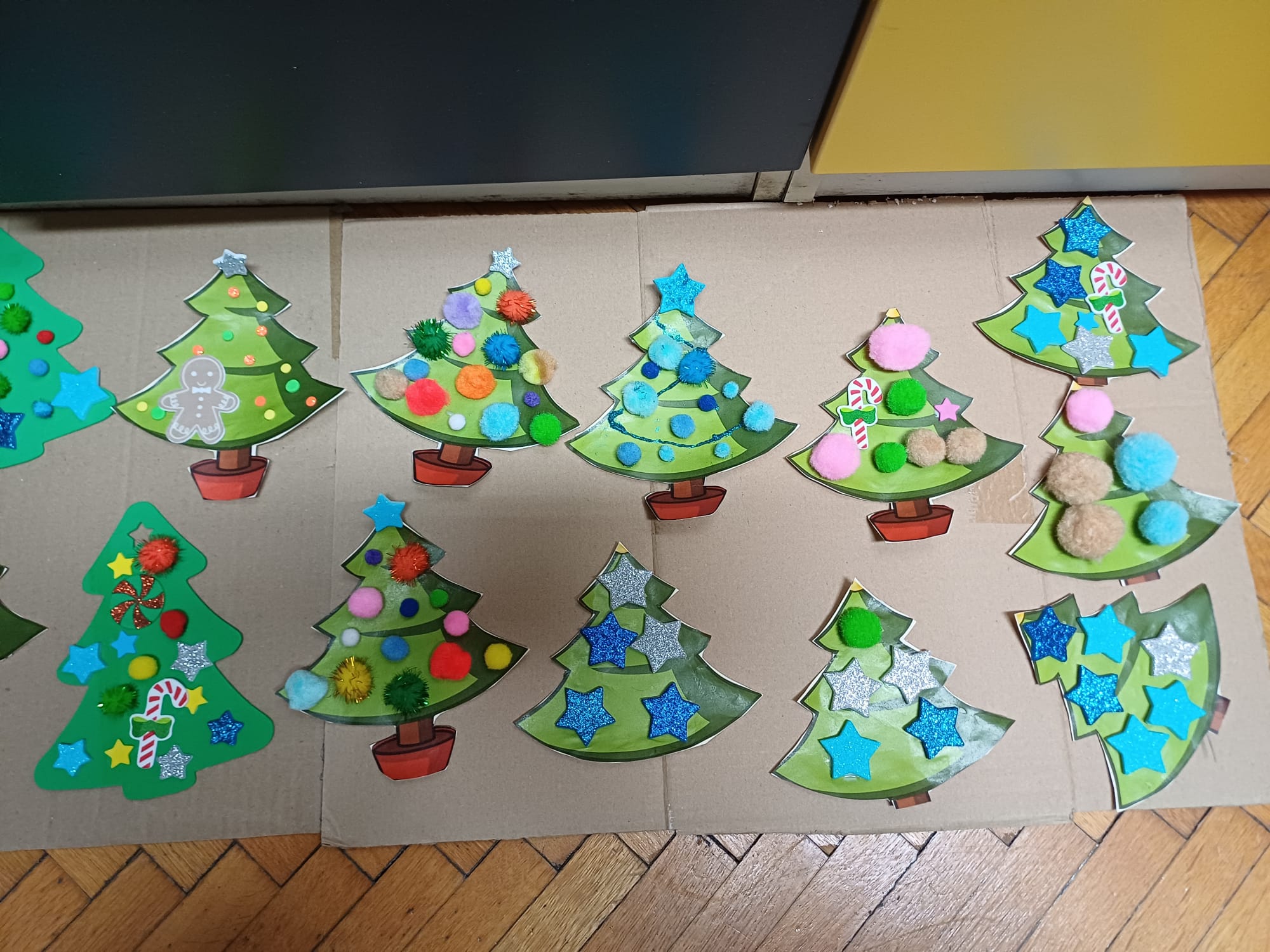 Na stolu su raspoređene gotove božićne jelke od kartona i kuglice od vune koje su izradili korisnici.